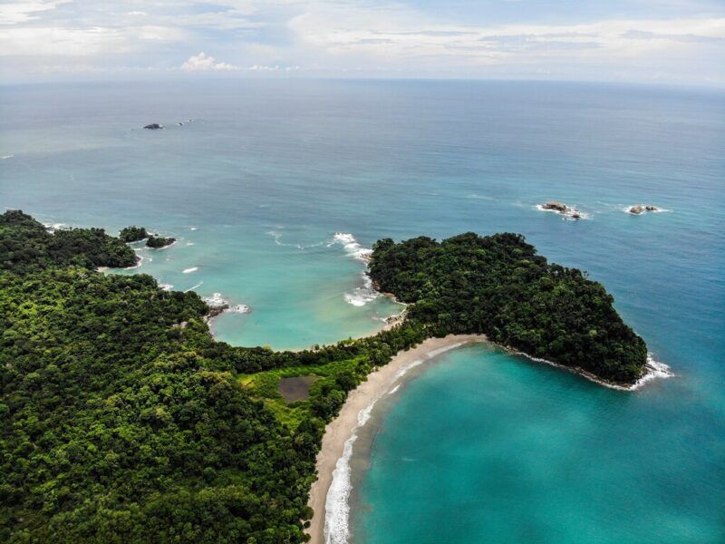 Aerial view of lush green rainforest and turquoise waters on the coastline of Costa Rica.
