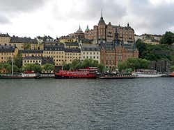 View of a red ferry sitting in the water in front of several traditional style buildings