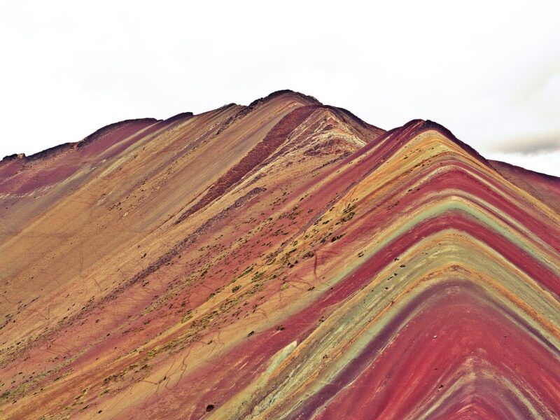 Rainbow Mountain in Peru showing vibrant stripes of red, gold, and green.