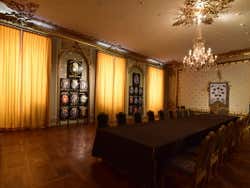 A long table in the centre of a room with crests on the walls and yellow curtains