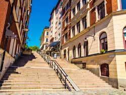 View looking up a staircase, lined with buildings leading to a vibrant blue sky,