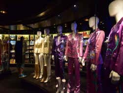 A line of ABBA costumes behind glass